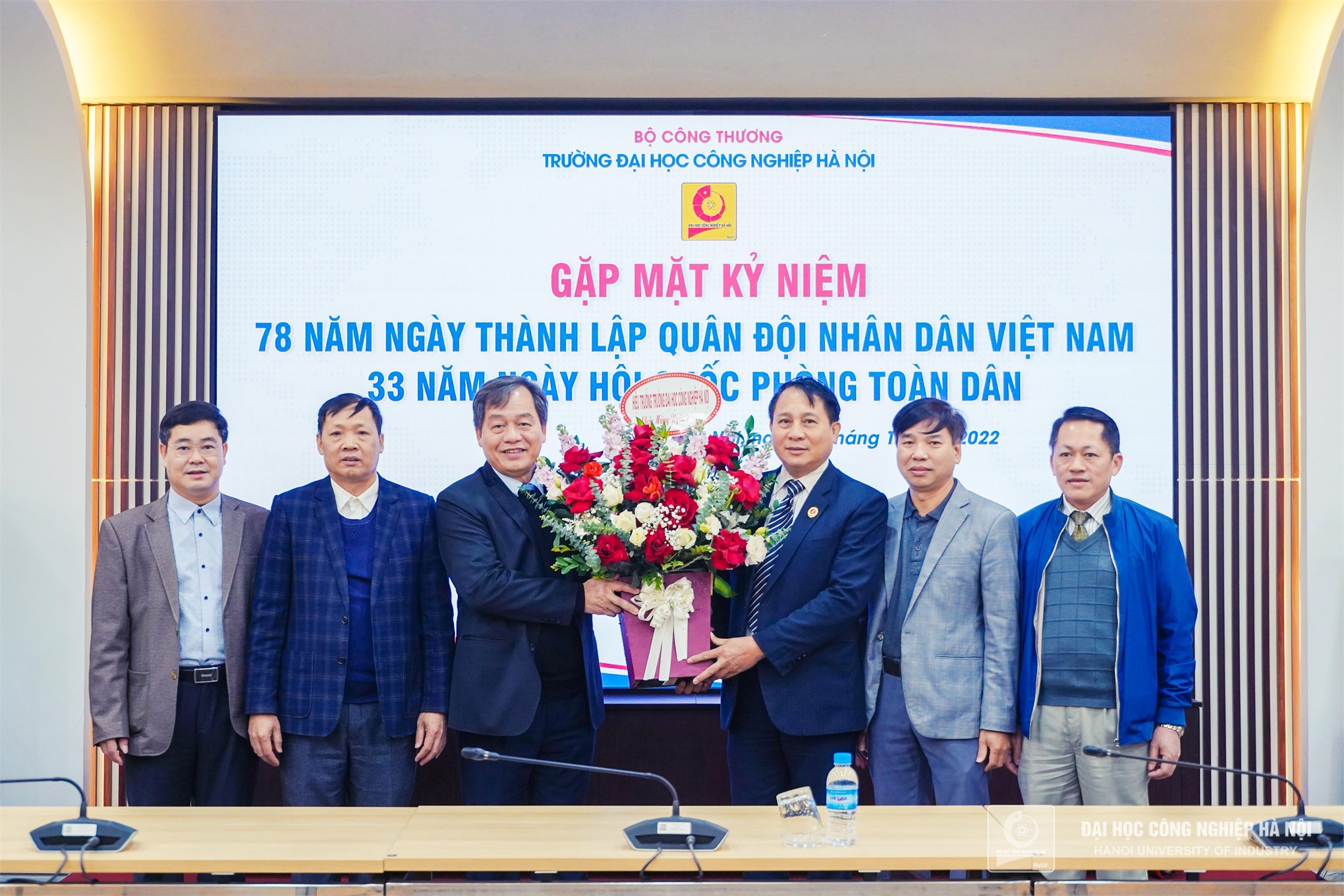 Assoc. Dr. Tran Duc Quy - Secretary of the Party Committee, and Rector of Hanoi University of Industry presents flowers to congratulate representatives of veterans of the university